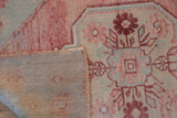 Folded corner of vintage distressed Oushak rug showing woven foundation and intact selvedge.