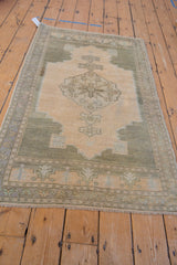 Distressed Oushak rug's secured fringe and muted olive, beige border detail.