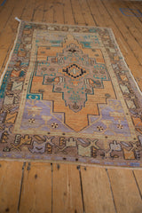 Distressed Oushak rug corner with geometric border in sandalwood, terracotta, and faded blue.