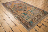 Distressed vintage Oushak rug corner, showing geometric floral border in muted terracotta and teal.