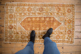 Distressed Oushak rug, showing copper and ivory pinwheel bud motifs and even wear.