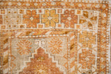 Distressed Oushak rug detail showcasing copper, gold, ivory pinwheel motifs and worn pile.