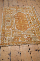 Vintage distressed Oushak rug corner shows textured copper, gold, and ivory geometric border.