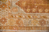 Distressed Oushak rug corner, warm copper, gold, ivory palette, with low pile.