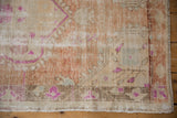 Vintage distressed Oushak rug corner, worn pile exposes foundation in sandalwood, copper, fuchsia.