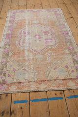 Textural detail of the distressed Oushak rug showcasing wear to knot heads and purple fuchsia blossoms.