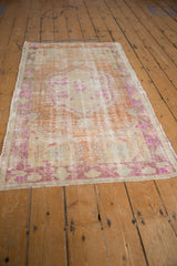 Vintage Distressed Oushak rug close-up showing central scalloped medallion with fuchsia florals.