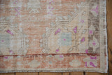 Distressed Oushak rug corner showing wear to foundation, abrashed pile, and fuchsia accents.