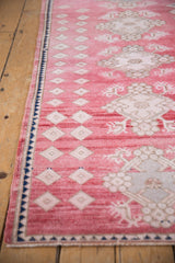 Blush red Oushak rug side with ivory concentric diamonds and navy selvage.
