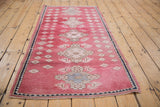Blush distressed Oushak rug corner with even wear, ivory motifs, and dark blue border.