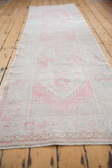 Distressed Oushak runner showing faded blush and ivory pile with even wear and side selvage.