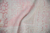 Faint foundation showing through distressed Oushak rug pile in blush and ivory.