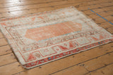 Distressed Oushak rug corner with exposed foundation, terracotta vines, and ivory finned leaf border.