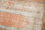 Distressed Oushak rug detail with worn terracotta pile, ivory ground, and meandering vine border.