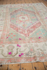 Distressed Oushak rug corner, showing stepped spandrel and floral border in softened tones.