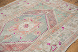Distressed pile of vintage Oushak rug showcasing seafoam, aubergine, and bold magenta outlines.