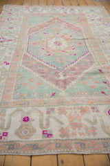 Distressed vintage Oushak rug corner showing wide border with floral and geometric motifs.