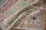 Vintage distressed Oushak rug texture, showing raspberry, seafoam, and aubergine motifs.