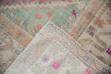 Distressed vintage Oushak carpet pile: seafoam, raspberry, violet, and visible woven foundation.