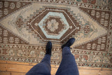 Distressed Oushak runner with stylized beige floral medallion and geometric stepped patterns.