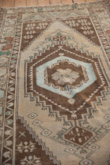 Distressed Oushak runner with muted blue medallion and chocolate brown stepped patterns.