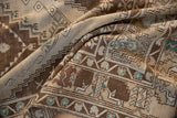 Distressed pile showing stepped geometric and floral motifs in beige, brown, and dusty blue.