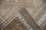 Distressed Oushak runner corner, showing its pale coffee brown pile, patterned border, and reverse.