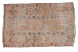 Distressed Oushak rug with faded rose and powder blue floral medallion, beige field.
