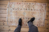 Distressed vintage Oushak rug, soft beige, pale blue, blush pink palette, with low worn pile.
