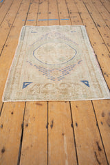 Corner of distressed Oushak rug, showing low pile, intact selvage, and cobalt blue motif.