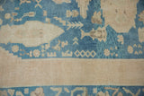 Distressed blue and beige Oushak rug border showing abstract flora and short pile.