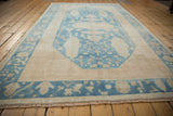 Distressed Oushak carpet's denim blue border featuring floral patterns and short end fringe.
