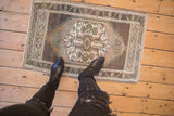 Distressed vintage Oushak rug corner, showing coffee brown and seafoam green vine border.