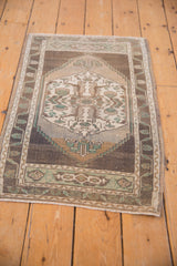 Distressed Oushak rug corner with coffee brown border, faded floral motifs, and even wear.