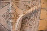 Distressed Oushak rug close-up showing even pile wear, stepped contour, and meandering vine motif.