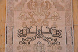 Distressed Oushak rug close-up: floral vinery, sand, charcoal tones, and soft even pile wear.