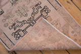 Curled corner of vintage Oushak rug showing hand knotted foundation and distressed floral design.