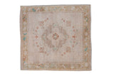 Distressed vintage Oushak square rug, ivory quatrefoil medallion, bronze border, faded blue accents.