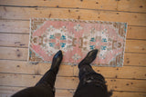 Distressed vintage Oushak mat, dusty rose, turquoise, bronze double medallion, with even wear.