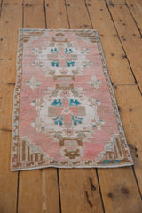 Distressed Oushak rug corner, showing even pile wear, intact selvage, dusty rose, and turquoise.
