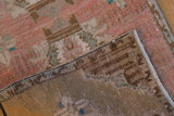 Distressed Oushak rug pile in dusty rose and pale bronze, revealing woven foundation.
