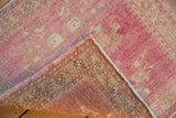 Distressed vintage Oushak rug corner revealing faded pink pile, abrash, and woven reverse with intact selvage.