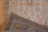 Folded corner of distressed Vintage Oushak rug, showing worn pile, hand-knotted reverse, and fringe.