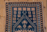 Distressed pile of a vintage Oushak rug, featuring cobalt blue geometric pattern and ivory pinwheel florals.