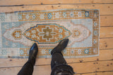 Distressed vintage Oushak runner's corner, with faded blue, bronze, and ivory geometric patterns.