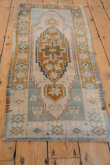 Distressed Oushak rug medallion and stepped spandrels in ivory, pale bronze, and teal.