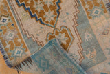 Vintage Oushak runner folded, showing distressed bronze and blue pile with teal woven reverse.