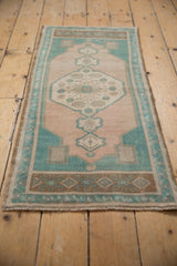 Distressed Oushak rug runner's inner starburst and floral motifs in pale ivory and dusty turquoise.