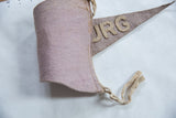 Curved view of the vintage Plattsburg felt pennant, highlighting felt texture and ties.