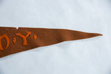 Tapered tip of the antique brown felt pennant with orange hand-sewn N.Y. letters visible.